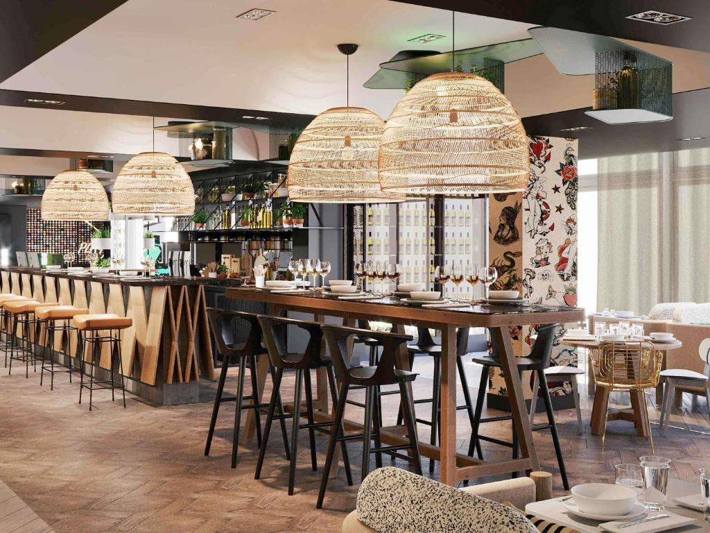 a restaurant with a large wooden bar with stools at Novotel Bordeaux Centre Ville in Bordeaux