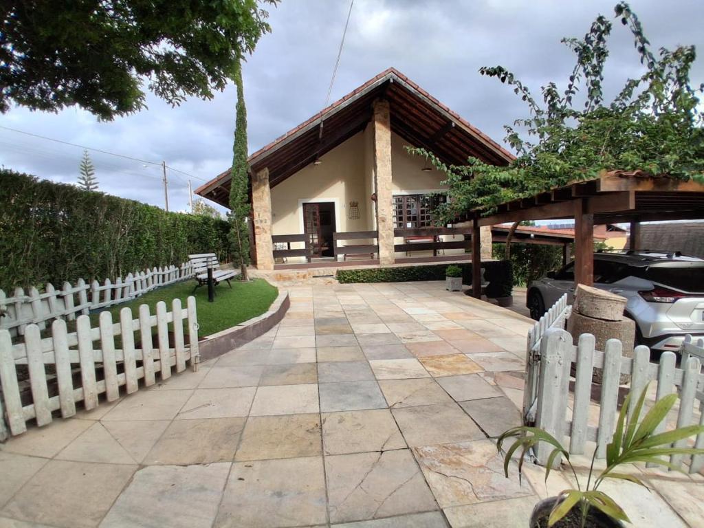 a white picket fence in front of a house at Chalé 4 Quartos Casa Jasmin in Chã Grande