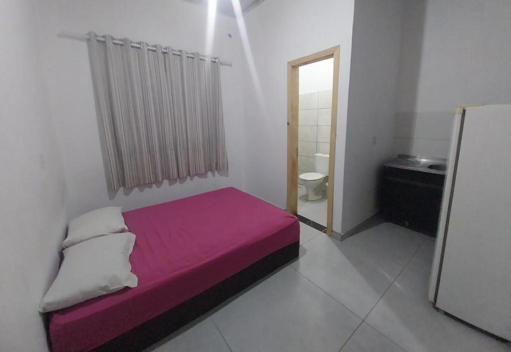 een kleine slaapkamer met een paars bed en een badkamer bij Pousada 201 in Caràzinho
