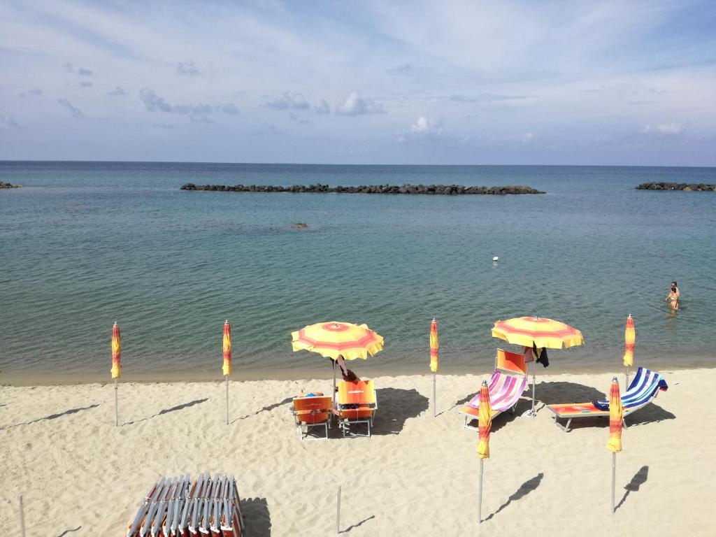 einen Strand mit Liegestühlen und Sonnenschirmen und dem Meer in der Unterkunft Pitosforo - Ulivo - Cocco in Ischia