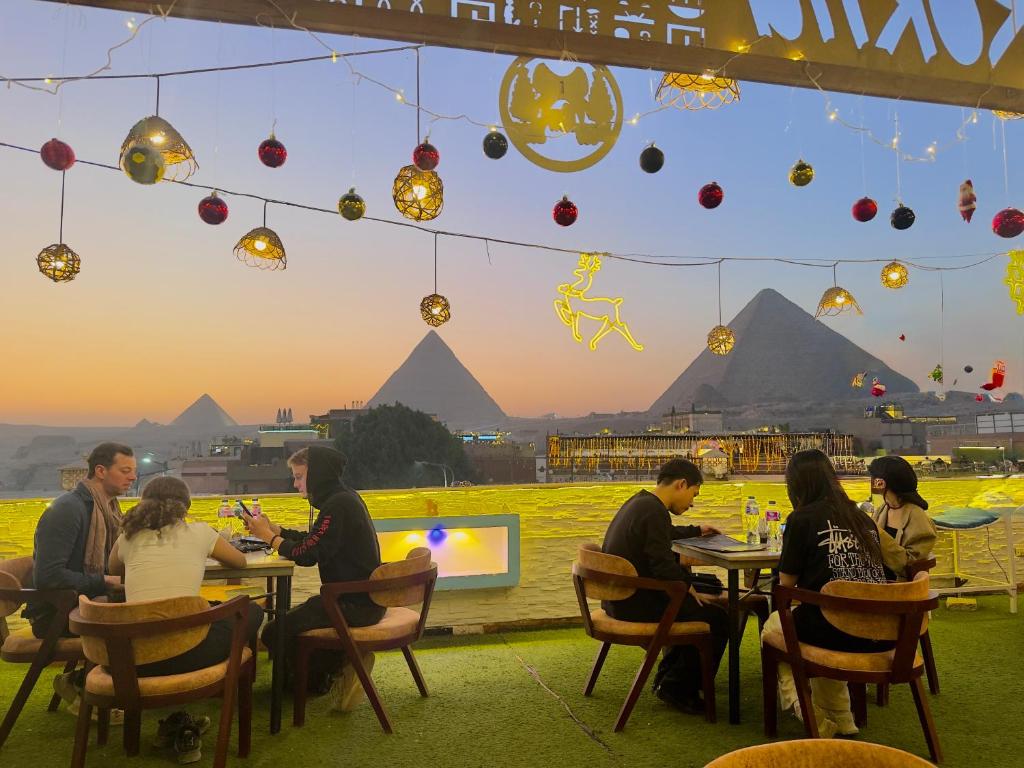 un gruppo di persone sedute ai tavoli davanti alle piramidi di Leeda Pyramids View a Il Cairo
