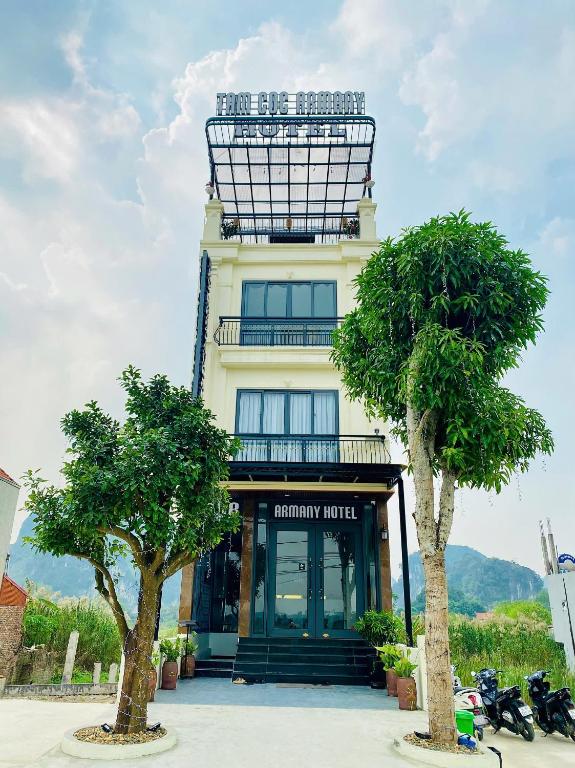 Un edificio con un cartel encima con dos árboles. en Tam Coc Armany Hotel & Sky Restaurant, en Vũ Lâm