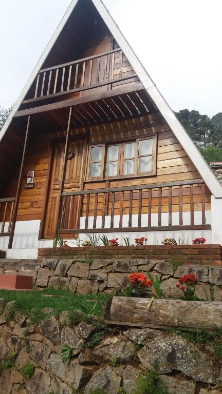 a wooden house with some flowers in front of it at Villa Valentina chalés com lareira e churrasqueira in Campos do Jordão