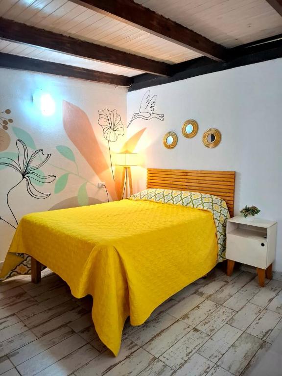 a bedroom with a yellow bed with a painting on the wall at Dona Monica in Ituzaingó