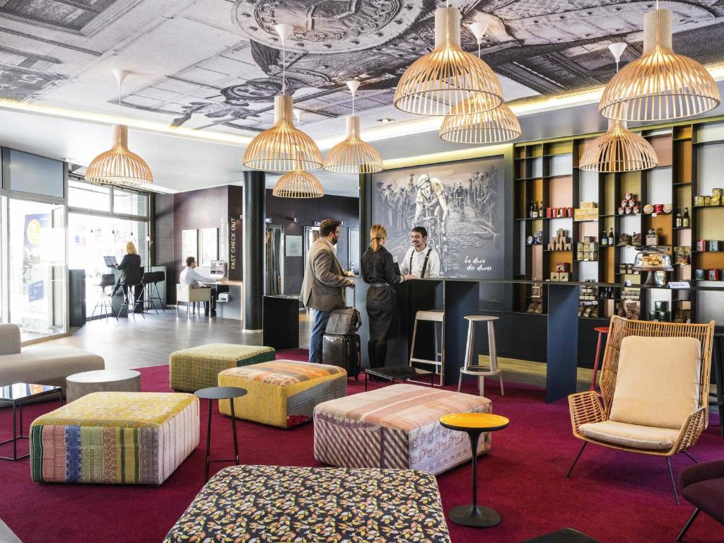 a lobby of a hotel with people standing at a bar at Novotel Lille Centre Gares in Lille