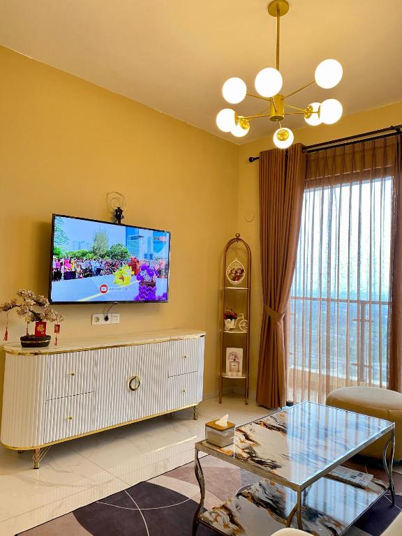 a living room with a flat screen tv on a yellow wall at Skyhouse bsd tower duxton 2 in Samporo