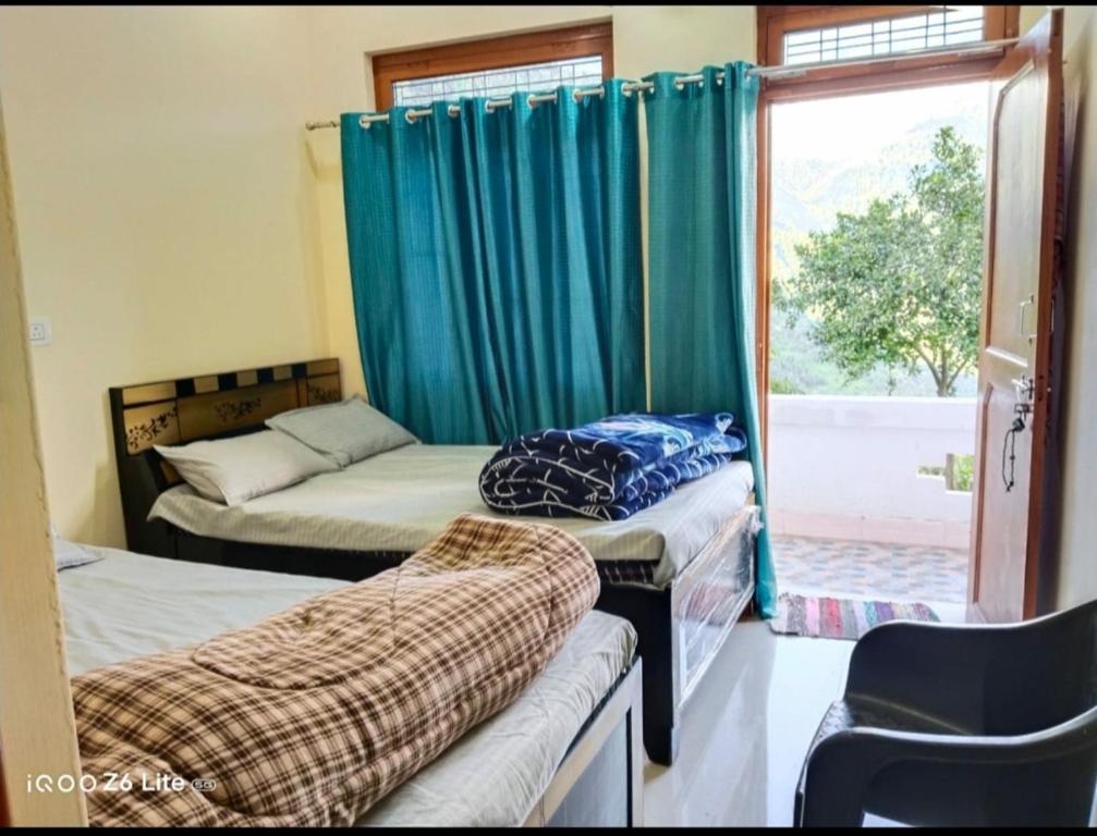 two beds in a room with a window at Himadri Homestay Sari Devriyatal in Sari