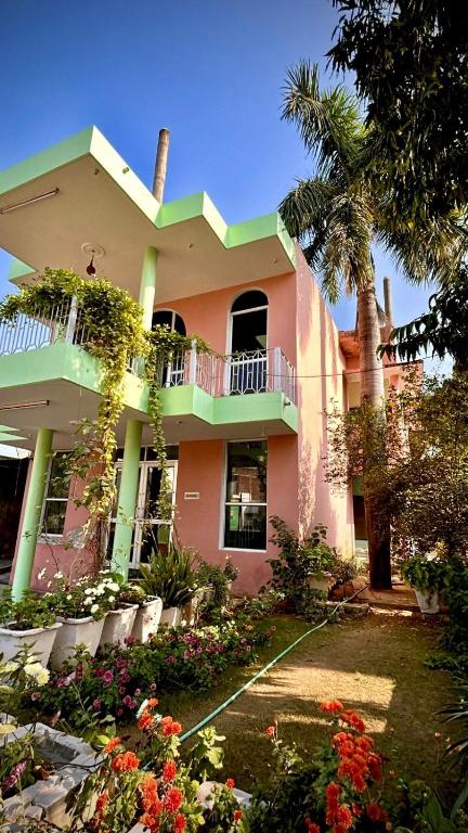 a large pink house with a palm tree and flowers at Hotel Spoonbbill in Bharatpur
