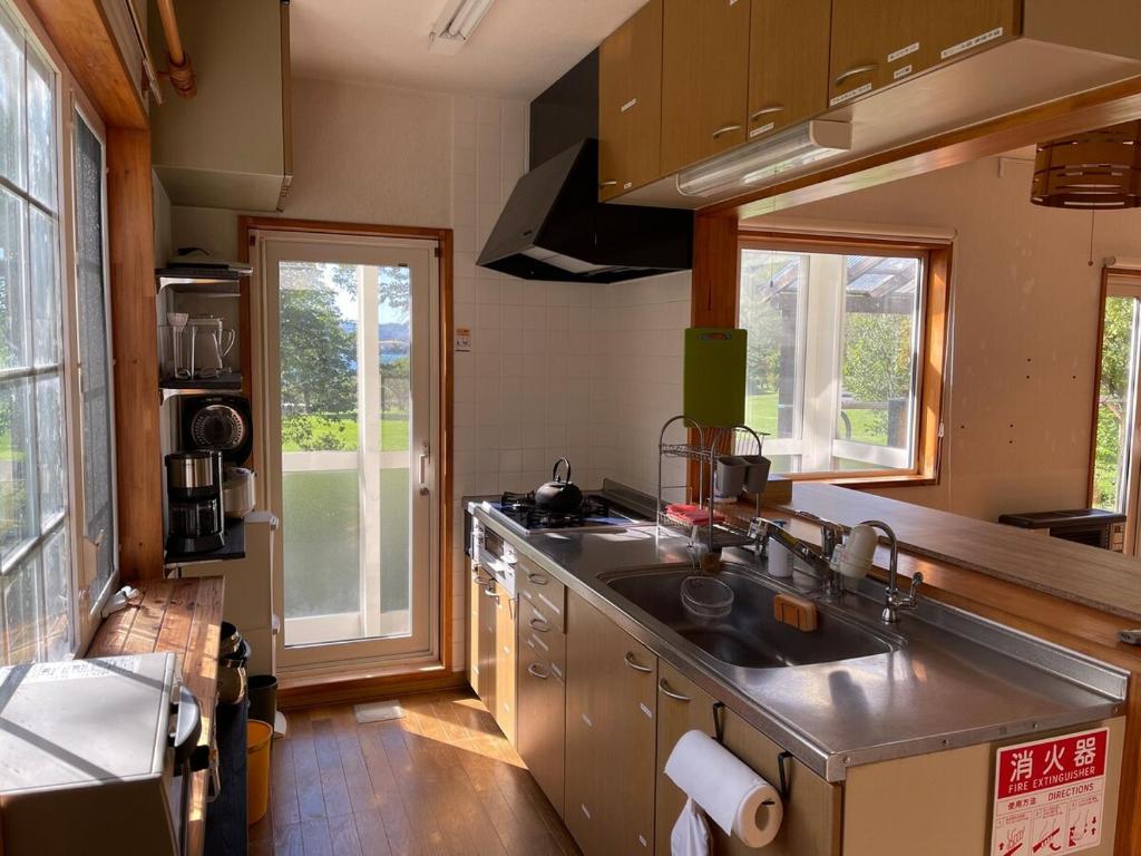 una cucina con un lavello e due finestre di aomame villa lake toya a Lago Toya