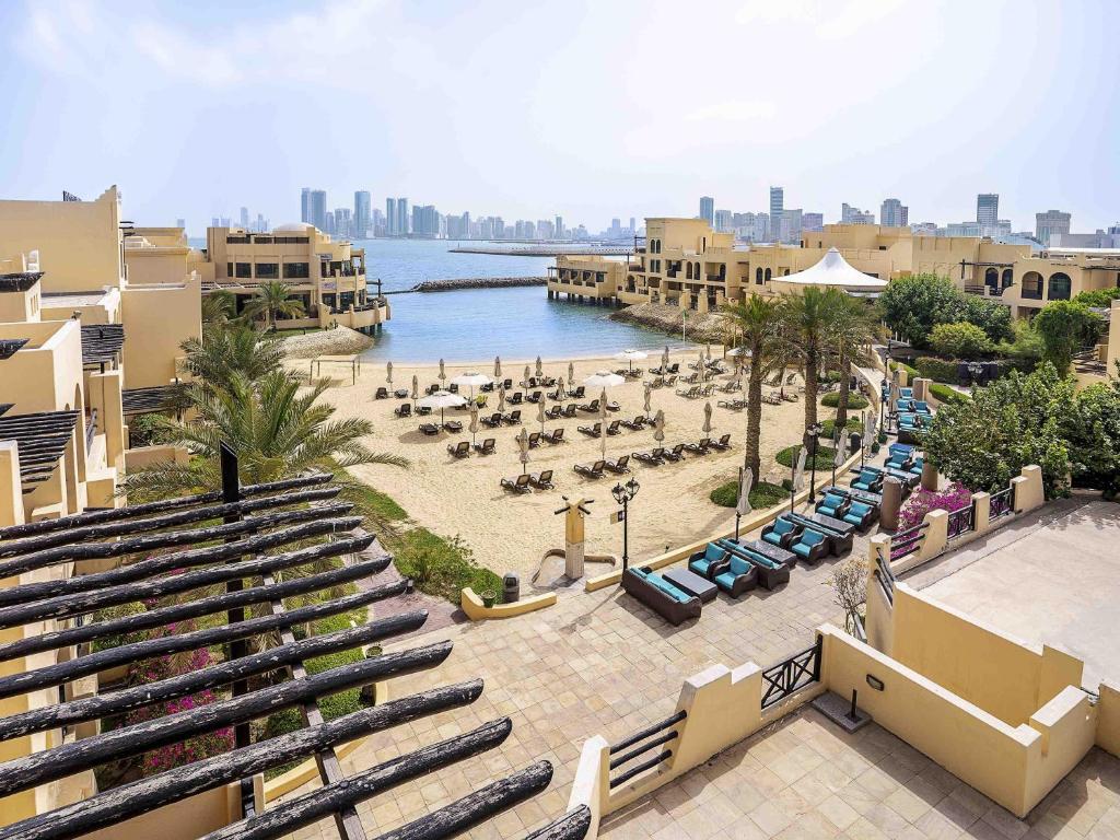 a view of a beach with chairs and a body of water at Novotel Bahrain Al Dana Resort in Manama