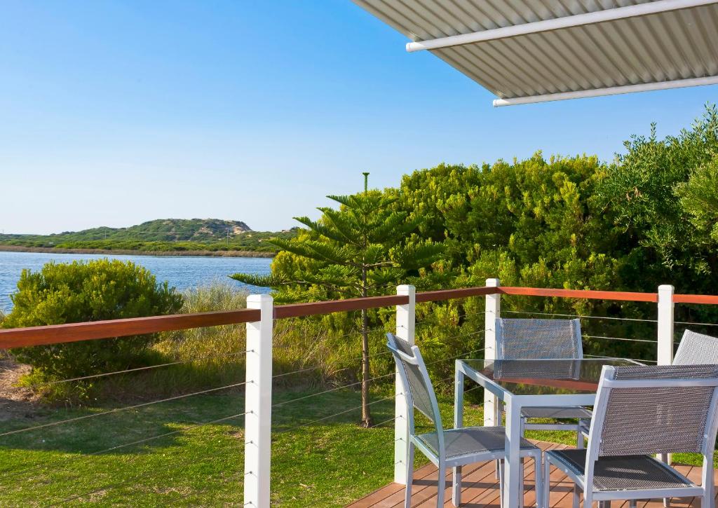a table and chairs on a deck with a view of the water at Great Ocean Road Tourist Park in Peterborough