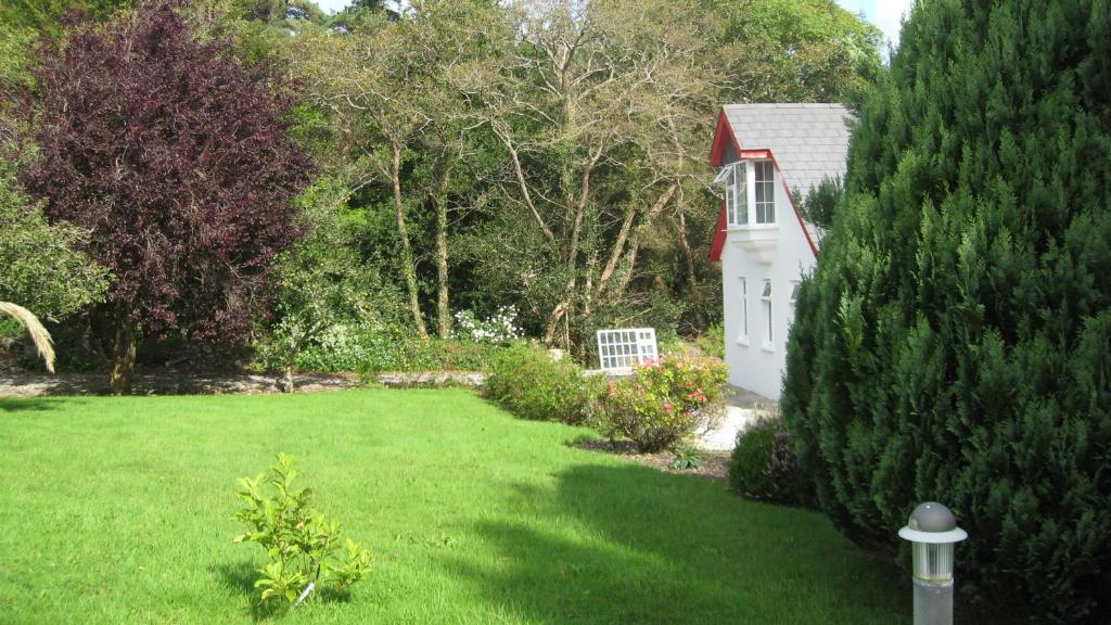 a green yard with a white house and trees at An Bruachan B&B in Kenmare