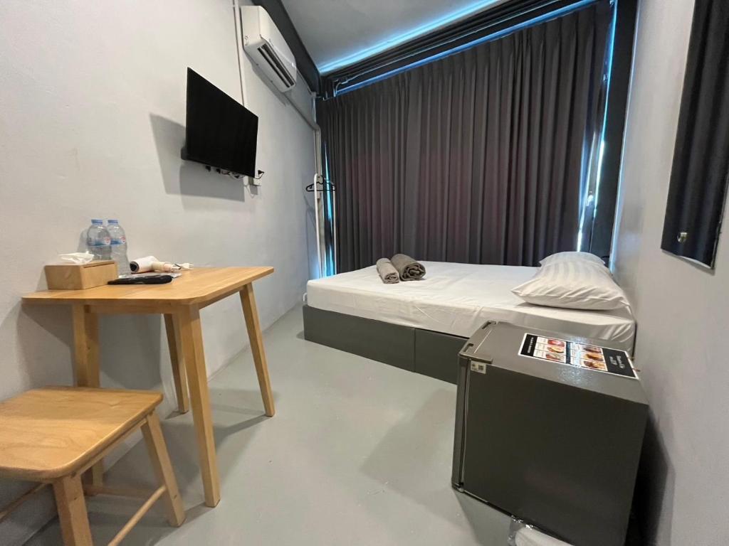 a small room with a bed and a small table at Udomsuk Inn & Cafe - BTS Udomsuk in Bangkok