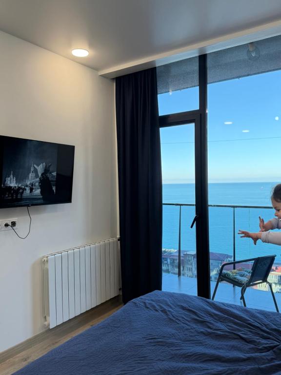 a bedroom with a bed and a view of the ocean at NBG Aparthotel in Batumi