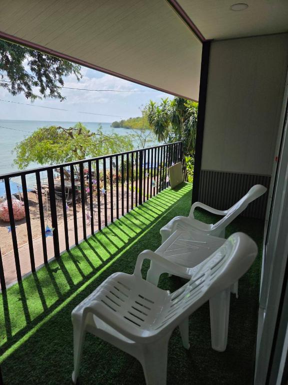 a balcony with two white chairs and a view of the ocean at Mong DOO SEA HOME in Ban Hua Phrong