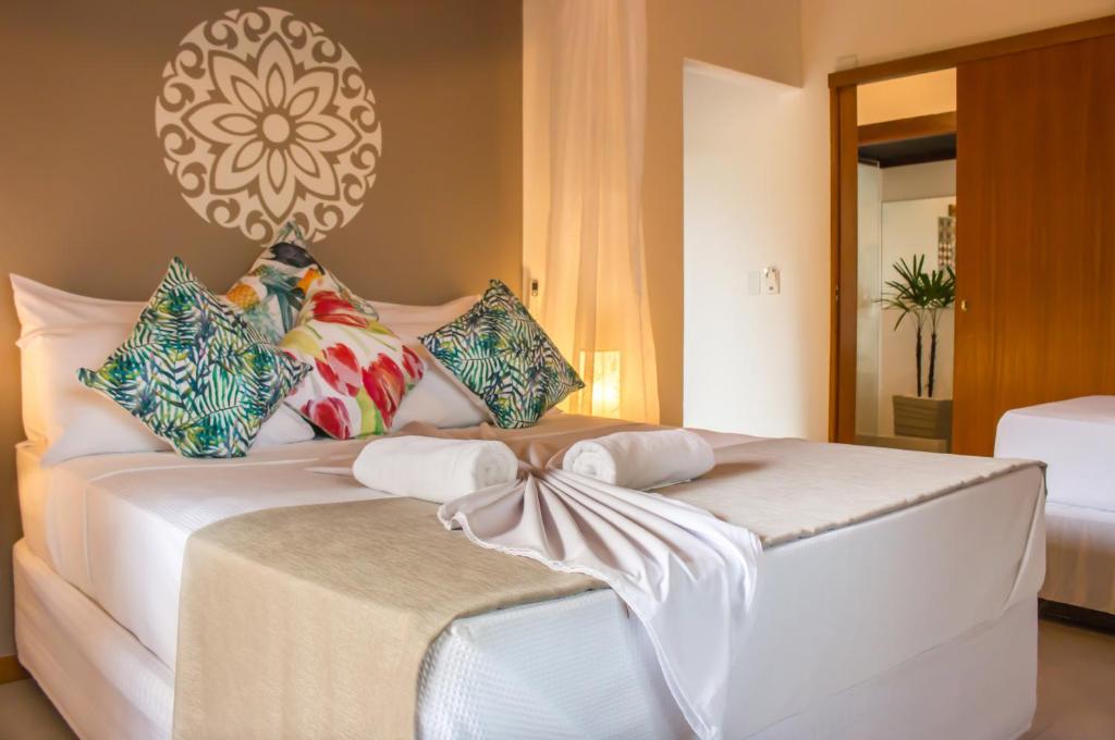 a white bed with pillows and a bow on it at Pousada e Chalés Aquarius in Arraial d'Ajuda