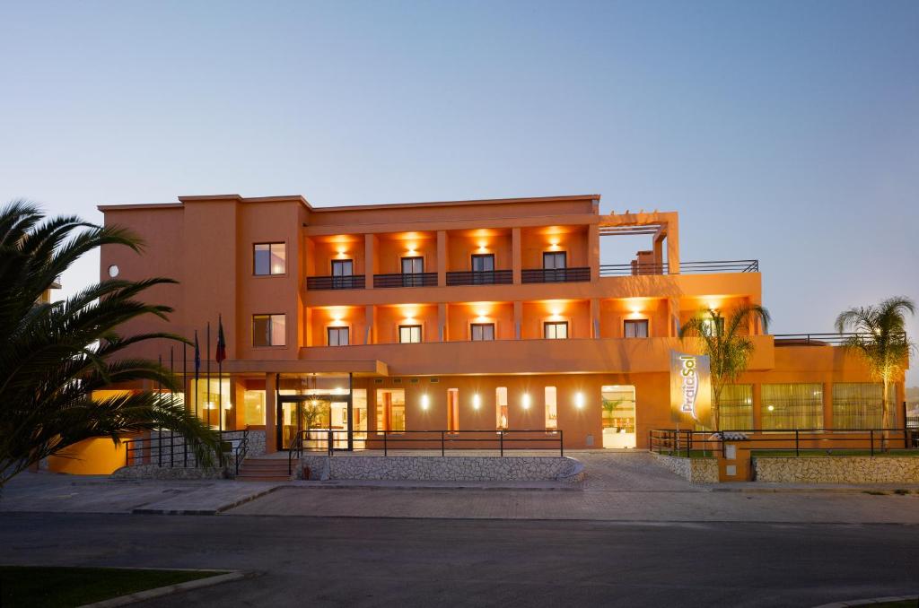 a building with lights on in front of it at Hotel Praia Sol in Quarteira
