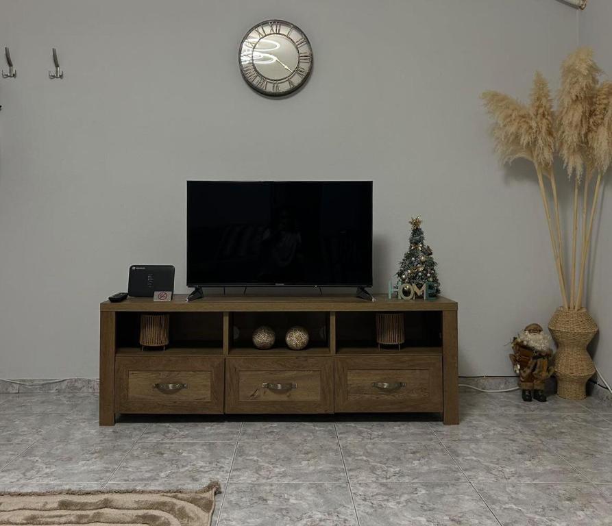una TV a schermo piatto seduta sopra un centro di intrattenimento in legno di Central Oasis a Alexandroupoli