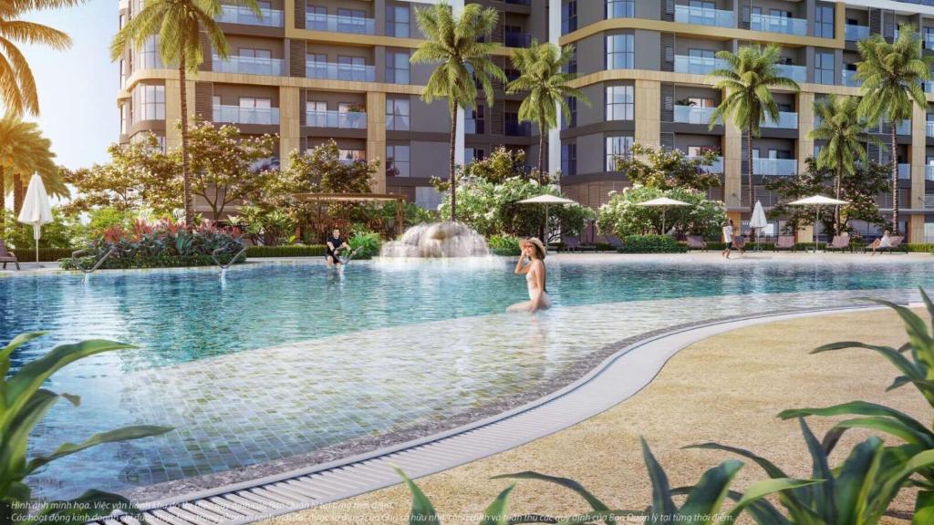 una donna in piedi in una piscina di fronte a un edificio di Vinhomes Grand Park the Beverly a Gò Công