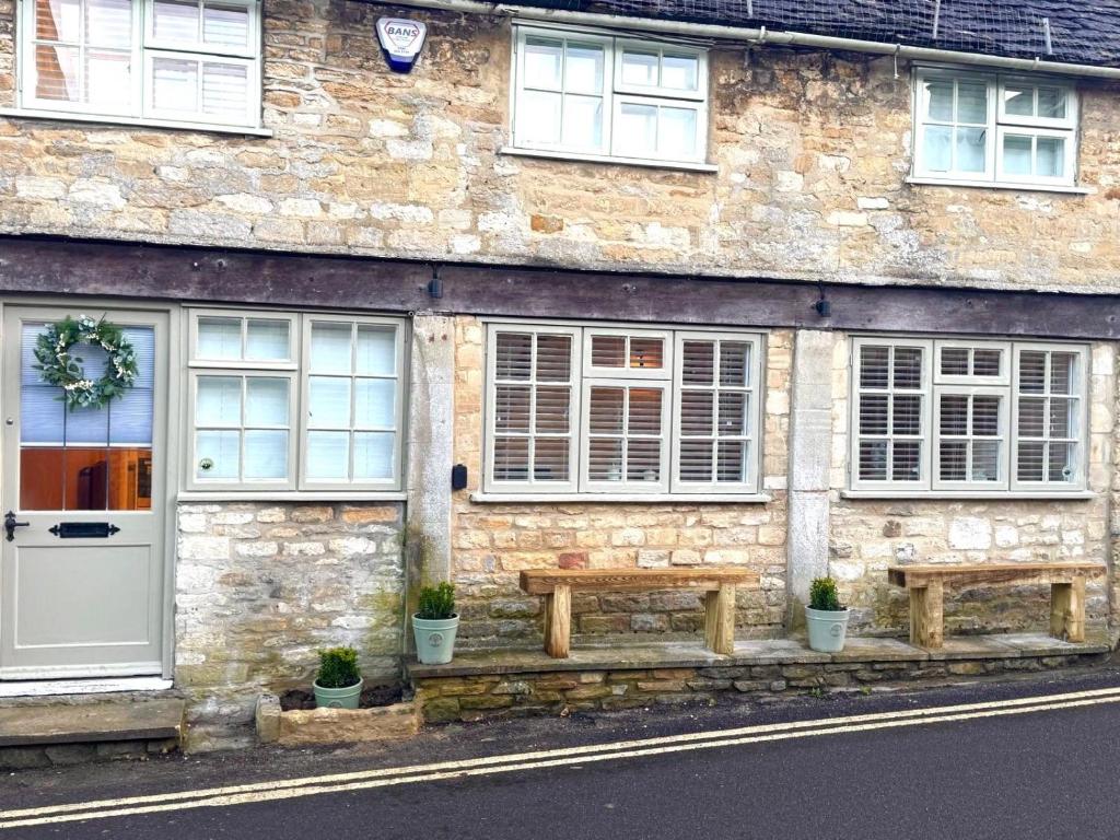 a stone building with a bench in front of it at Priory Weavers Cottage in Burford