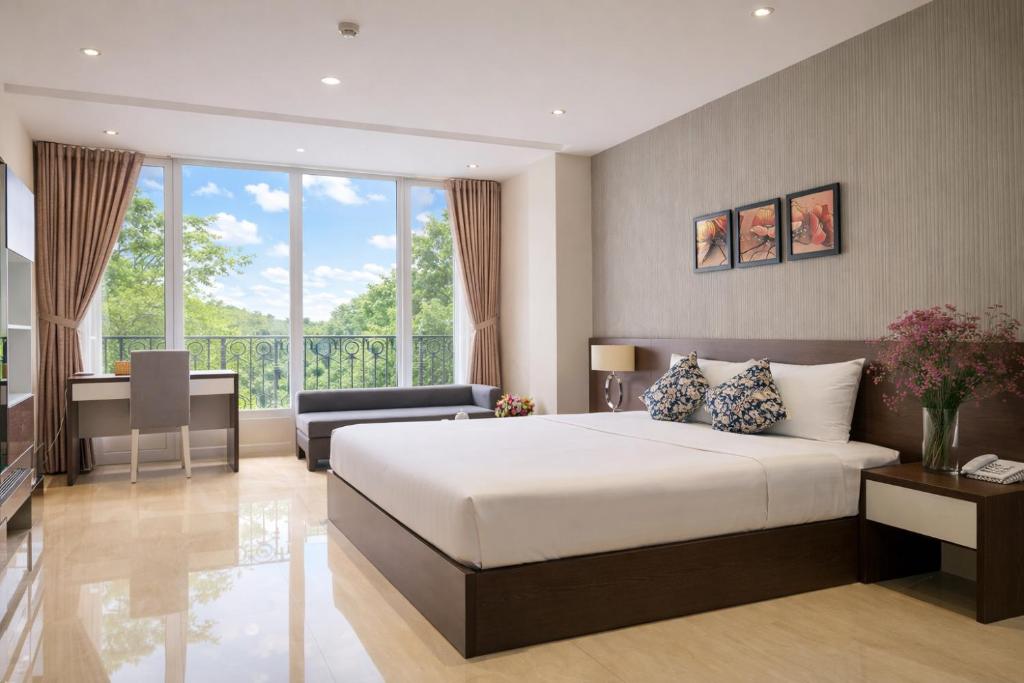 a bedroom with a large white bed and a desk at Golden Queen Aparthotel in Ho Chi Minh City