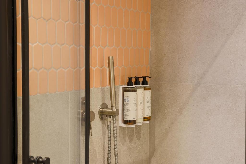 two bottles of essential oils sitting on a shower door at Jrose Hotel in Jerusalem