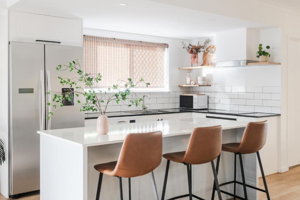 een keuken met een wit aanrecht en 3 krukken bij Whitsunday Wanderluxe in Cannonvale