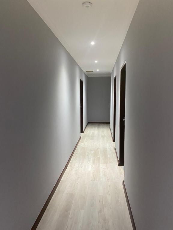 an empty hallway with white walls and wooden floors at Pluto Guesthouse in Walvis Bay