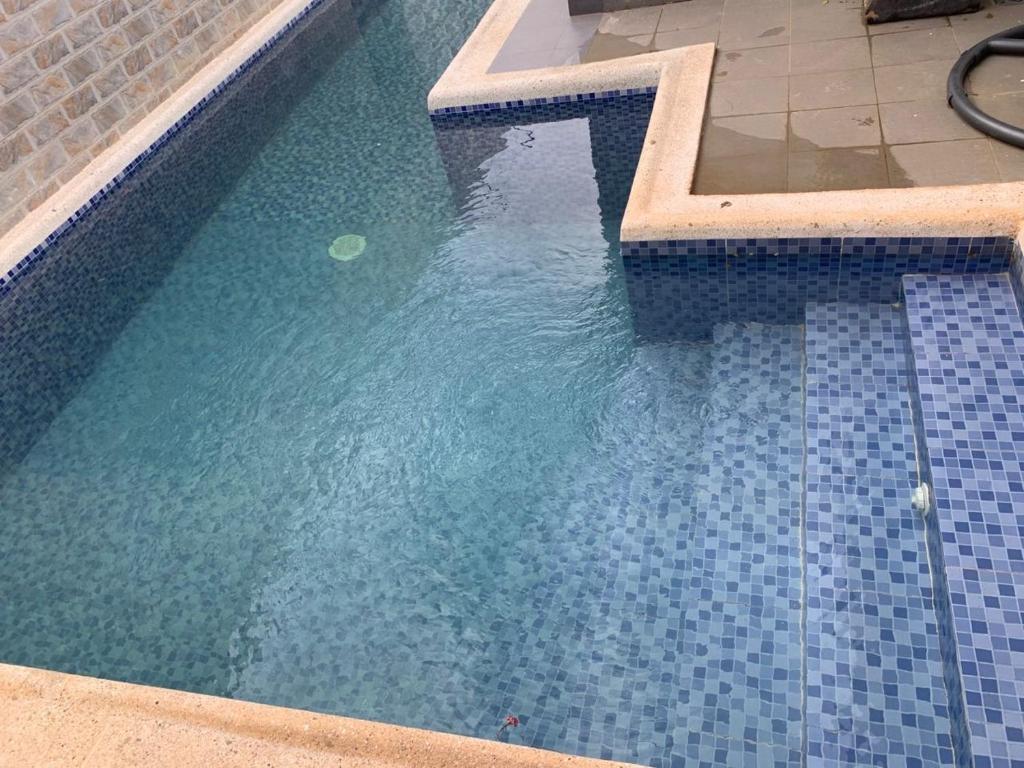 a swimming pool with blue tiles in the water at Maison de vacance Saly in Mbour