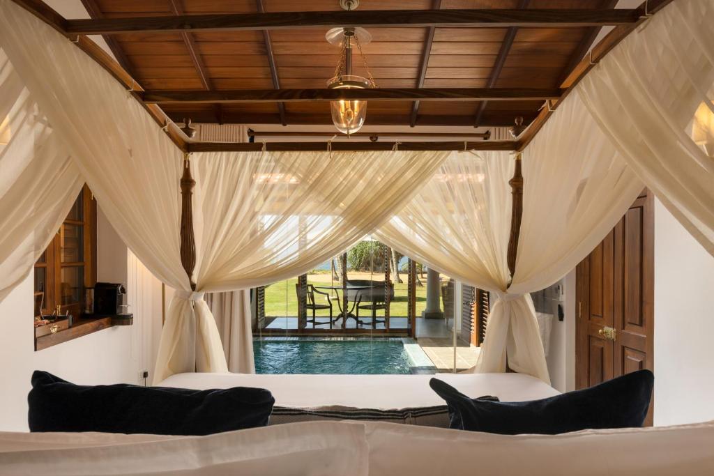 a bedroom with a bed with curtains and a patio at Oruva Beachside Villa in Galle