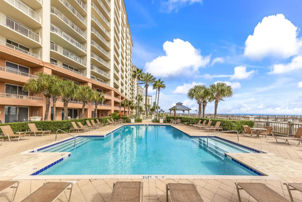 una piscina in un resort con sedie e l'oceano di Beach Club Condos a Gulf Shores
