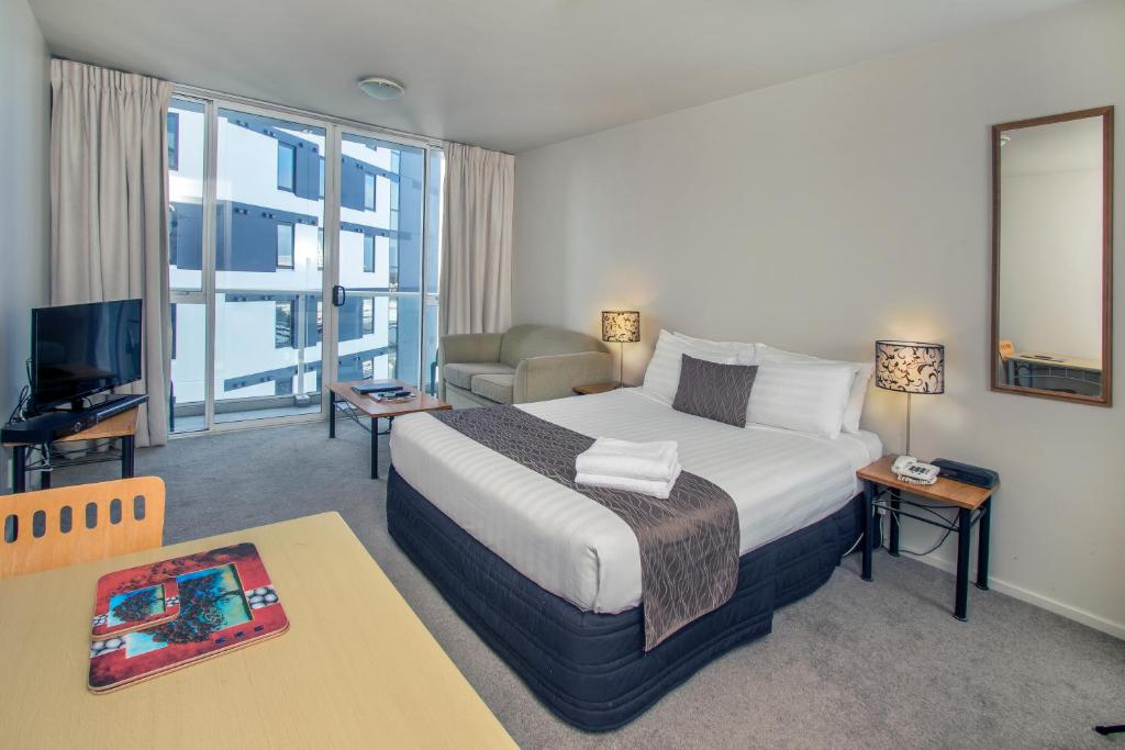 a bedroom with a large bed and a living room at Crown on Cintra Lane in Auckland