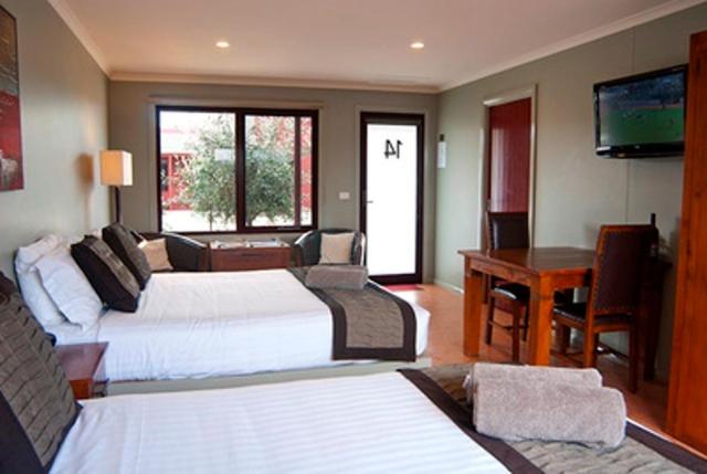 a hotel room with two beds and a desk at Bairnsdale Motel in Bairnsdale