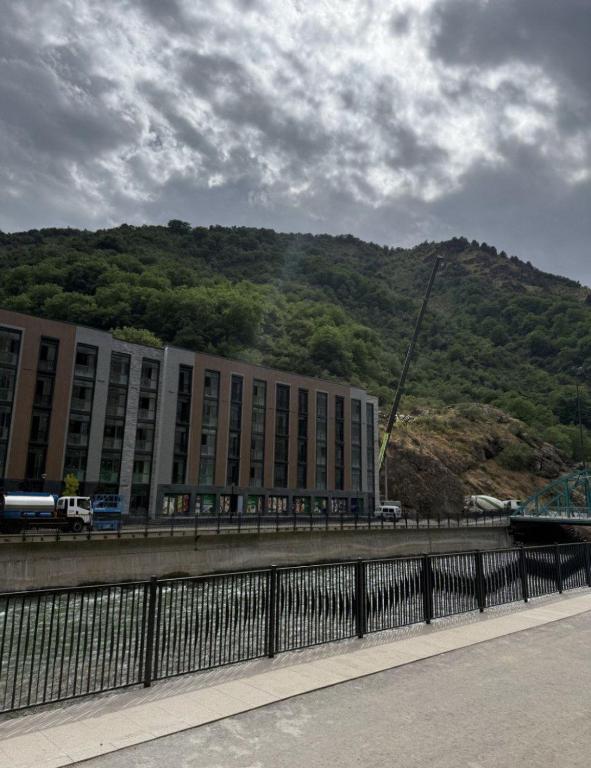 a large building with a mountain in the background at Ugam Mountain apartments in Khumson