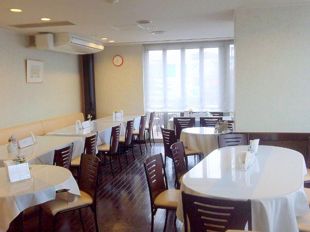 岡谷市にある岡谷セントラルホテル のダイニングルーム(白いテーブル、椅子付)