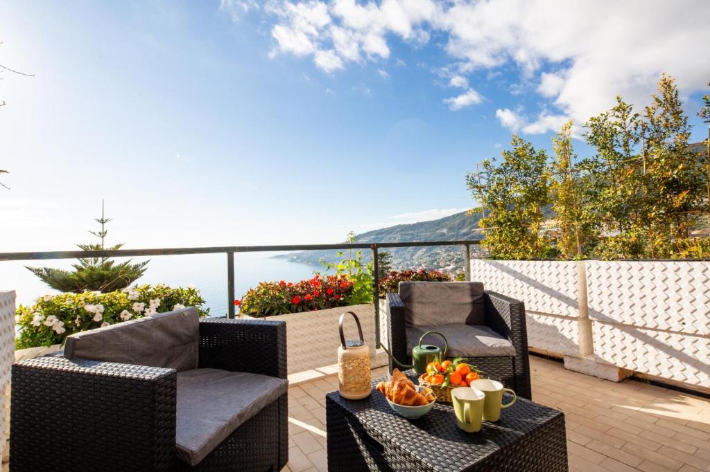 Un patio con dos sillas y una mesa con fruta. en Infinity Blue - Sunny Coastal Apartment, en Ospedaletti