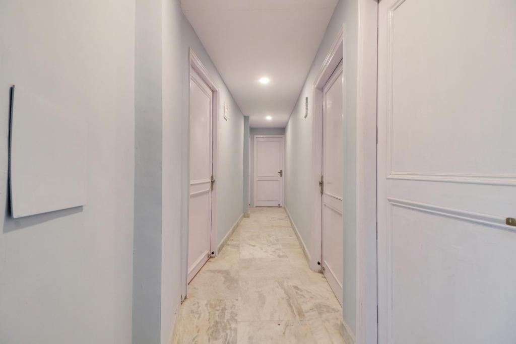 un pasillo con paredes blancas y una puerta en Hotel O by OYO Blue moon, en Nueva Delhi