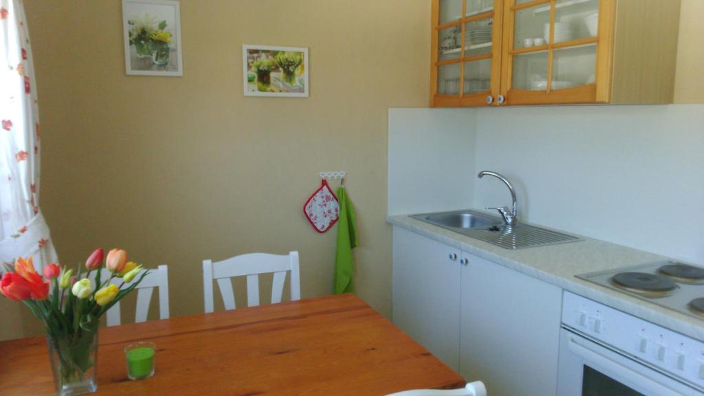 una cocina con fregadero y una mesa con un jarrón de flores en Ferienwohnung Frühlingsau, en Freudenstadt