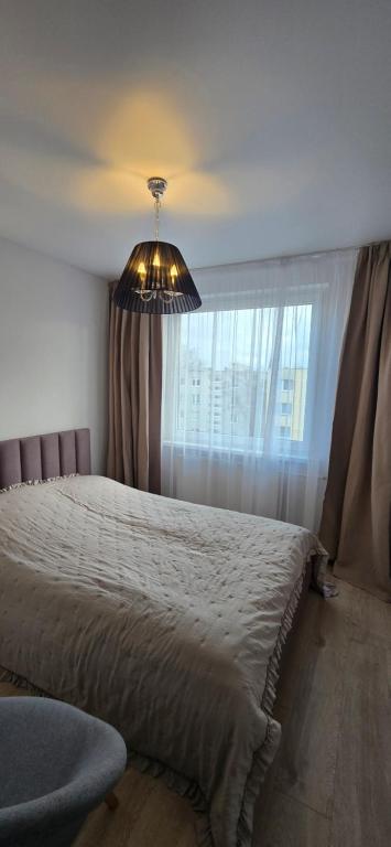 una camera da letto con un letto e una grande finestra di Mažeikiai City Apartments a Mažeikiai
