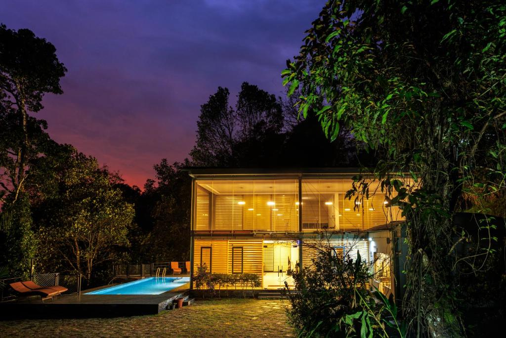 een huis met een zwembad in de nacht bij Stallion Estates in Munnar