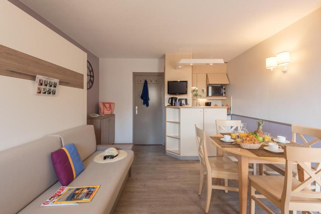 ein Wohnzimmer und eine Küche mit einem Sofa und einem Tisch in der Unterkunft Résidence Pierre & Vacances La Promenade des Bains in Saint-Raphaël
