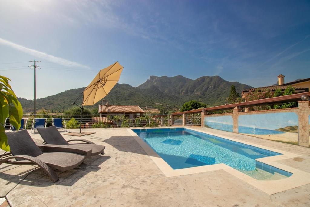 a swimming pool with two chairs and an umbrella at S'Omu e Assunta in Cardedu