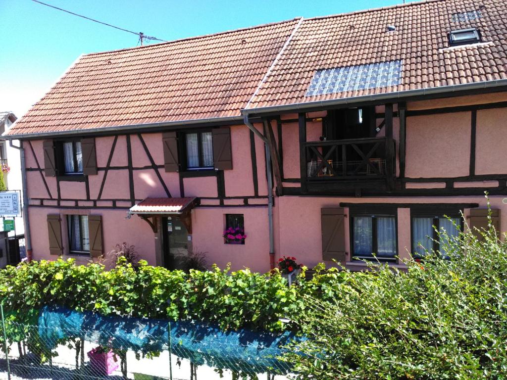 une maison rose avec un balcon et quelques buissons dans l'établissement Gites & Camping on the Route des Vins, à Bergheim
