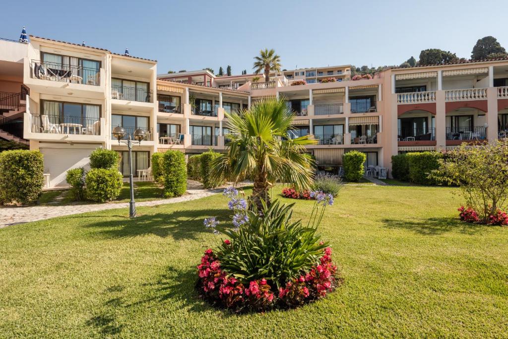 an apartment building with a palm tree in a yard at Résidence Pierre & Vacances l'Ange Gardien in Villefranche-sur-Mer