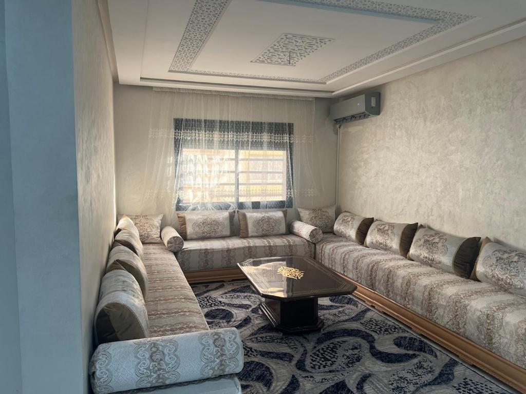 een woonkamer met een grote bank en een tafel bij Luxury University Apartment 3 in Fès