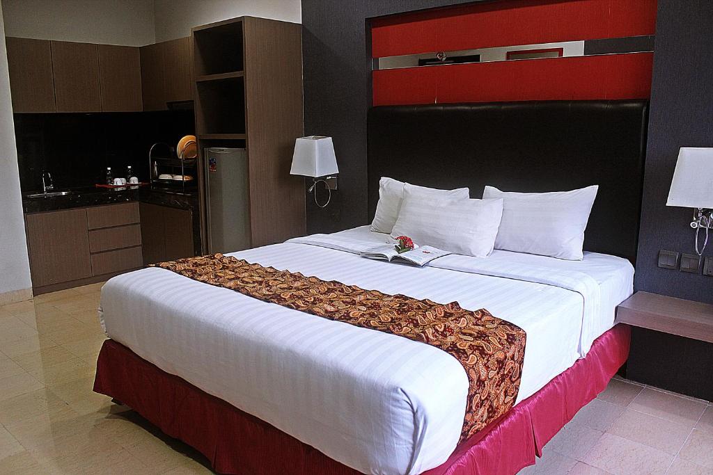 a bedroom with a large bed with a red and white headboard at The Centro Hotel & Residence By Orchardz in Batam Center