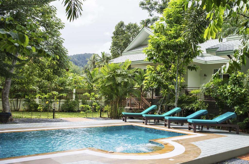 ein Pool mit blauen Bänken neben einem Haus in der Unterkunft Baan Aree Villa in Klong Muang Beach