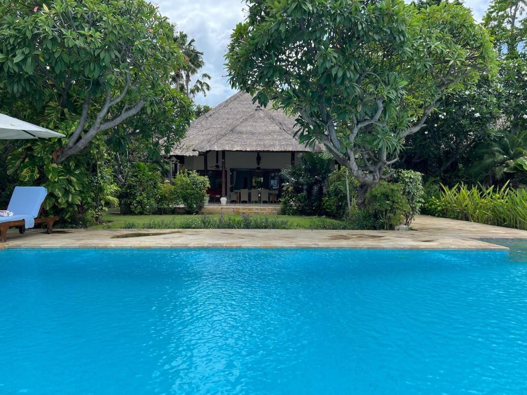een resort met een blauw zwembad en een huis bij Beachfront Villa Mawar with Private Pool and Sunset View in Pengastulan