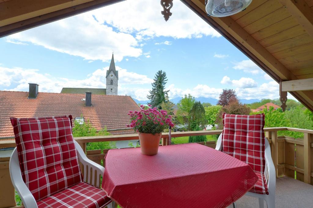 un tavolo rosso e sedie su un balcone con una torre dell'orologio di TraumWohnung a Seebruck