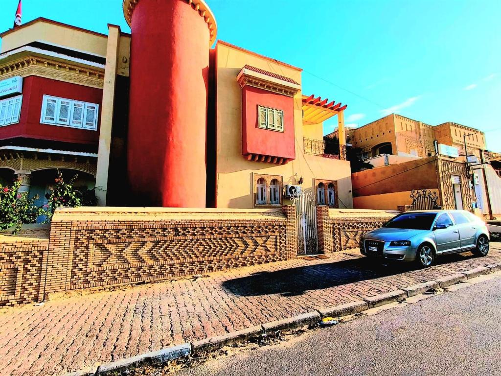 ein Auto, das auf einer Straße neben einem Gebäude geparkt ist in der Unterkunft Dar Jana Tozeur in Tozeur